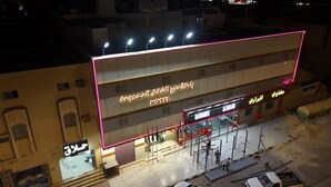 A hotel with a neon sign, a bus stop, and construction equipment. - Rahet Al-Kharj Serviced Apartments (Al Kharj)