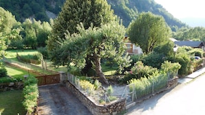 A rural setting with a stone wall, a wooden gate, and a paved road.