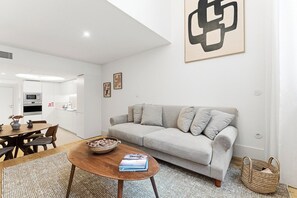 A modern living room with a sofa, coffee table, and a dining area with chairs and a table. - Unique Luxury and Quiet in Porto’s Best Location (Porto)