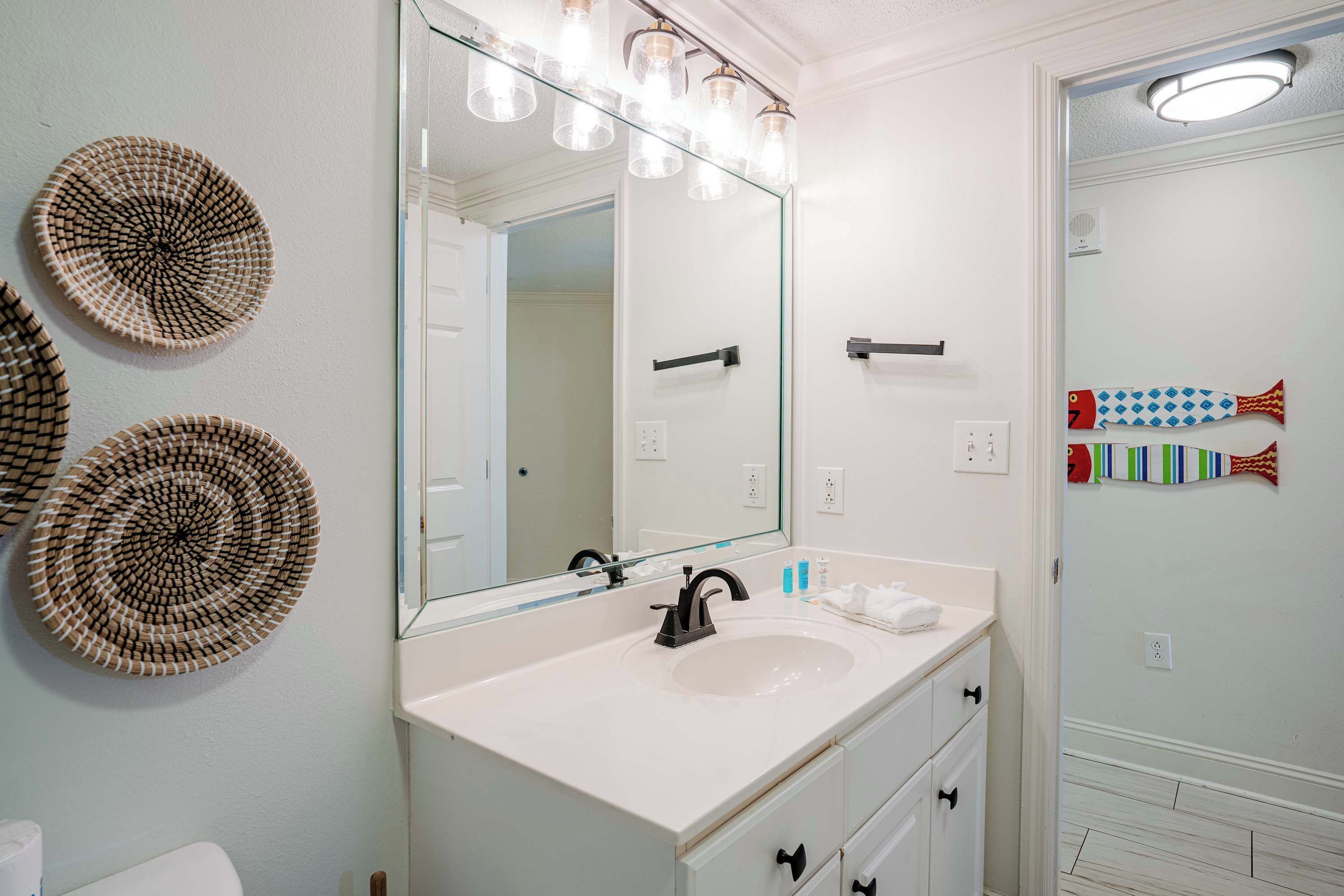 A bathroom with a white sink, a large mirror, and decorative wall plates.