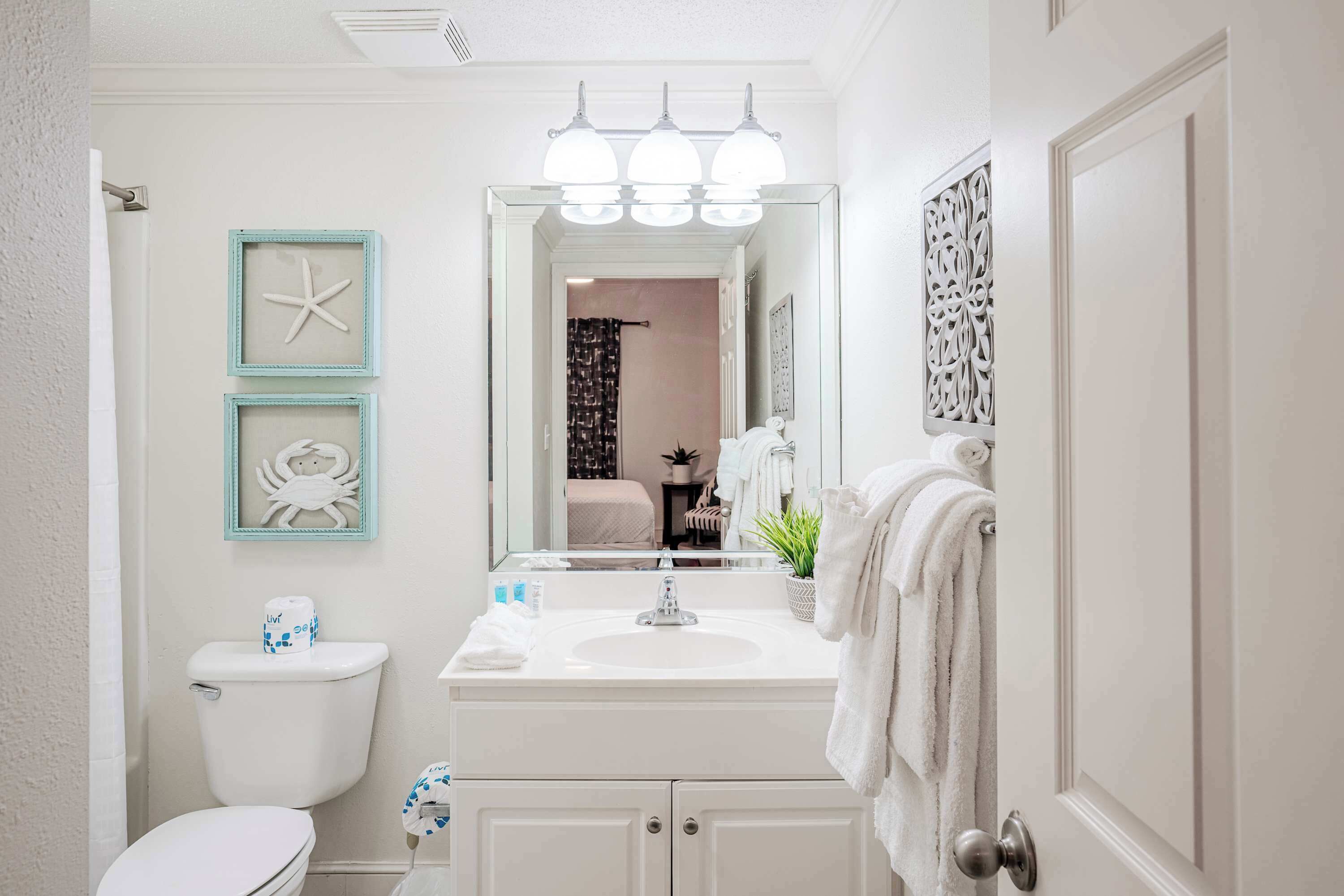 A bathroom with a toilet, sink, and mirror. There are starfish decorations on the wall and a towel rack.