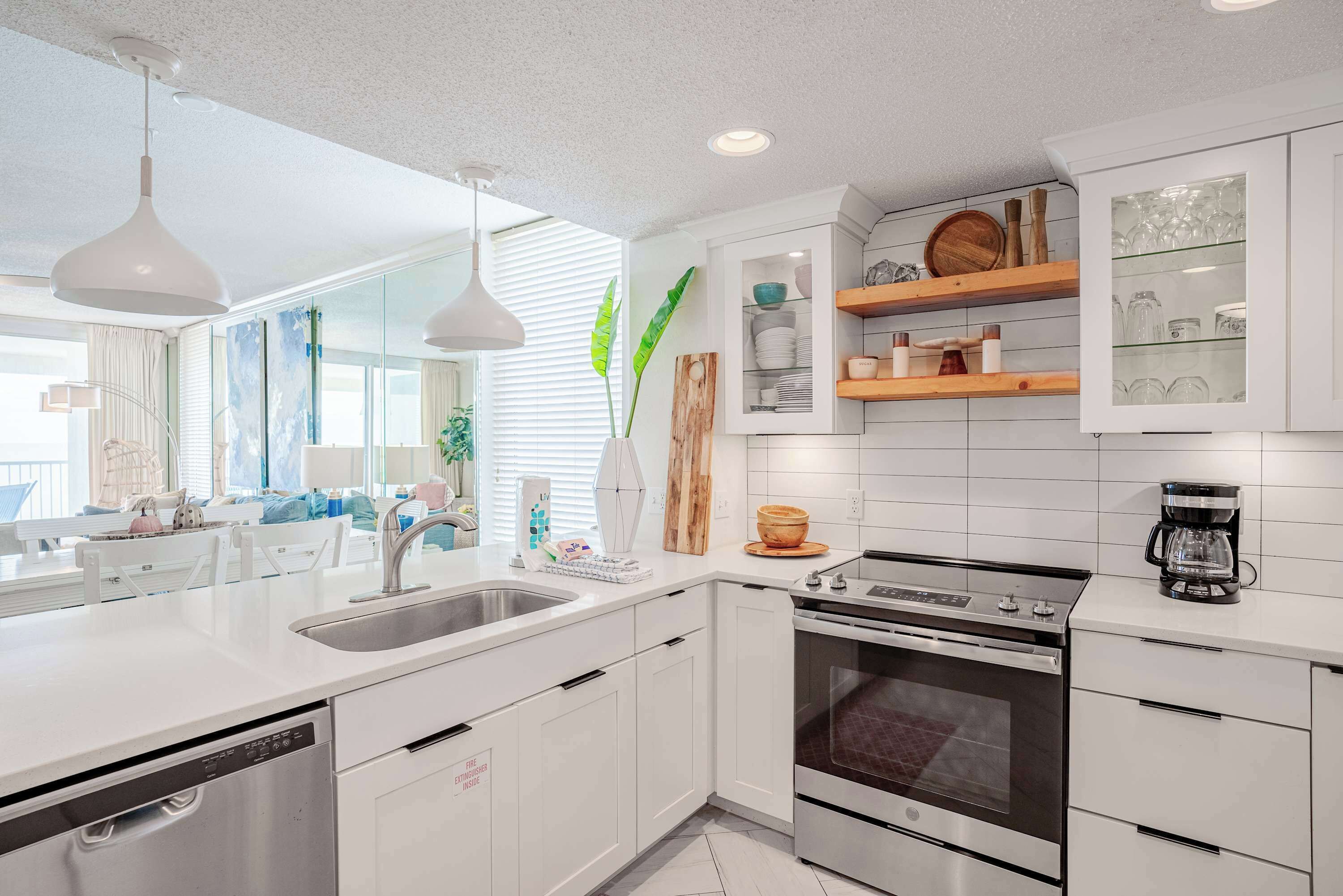 A modern kitchen with white cabinetry, a stainless steel dishwasher, a double oven, and a coffee maker on the countertop.