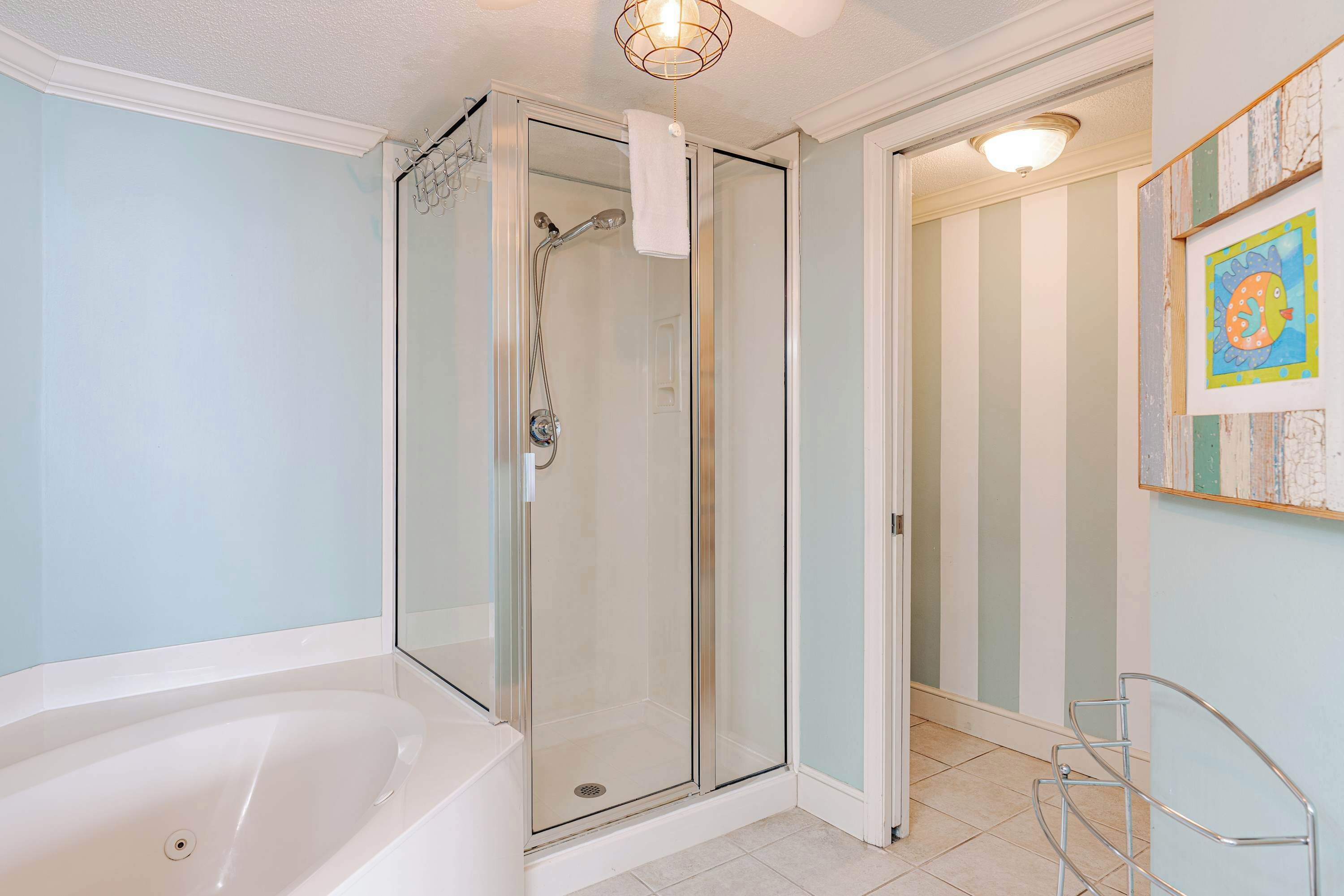 Un baño moderno con ducha de vidrio, bañera blanca y paredes a rayas.