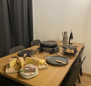 A dining table set with plates, cutlery, glasses, a bottle of wine, a bowl of potatoes, and a cheese board. - T2 with pool in Saint-Gervais-les-Bains (Saint-Gervais-les-Bains)