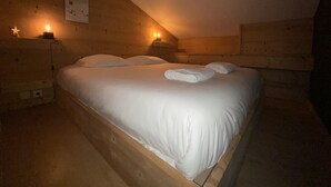 Een houten kamer met een bed, twee nachtkastjes en een wandlamp.
