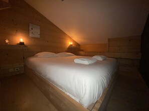 A wooden room with a bed, two bedside tables, and a wall-mounted light fixture. - T2 with pool in Saint-Gervais-les-Bains (Saint-Gervais-les-Bains)