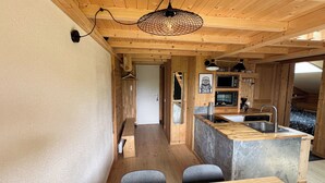 Een kleine keuken met houten kastjes, een ingebouwde magnetron en een spoelbak.