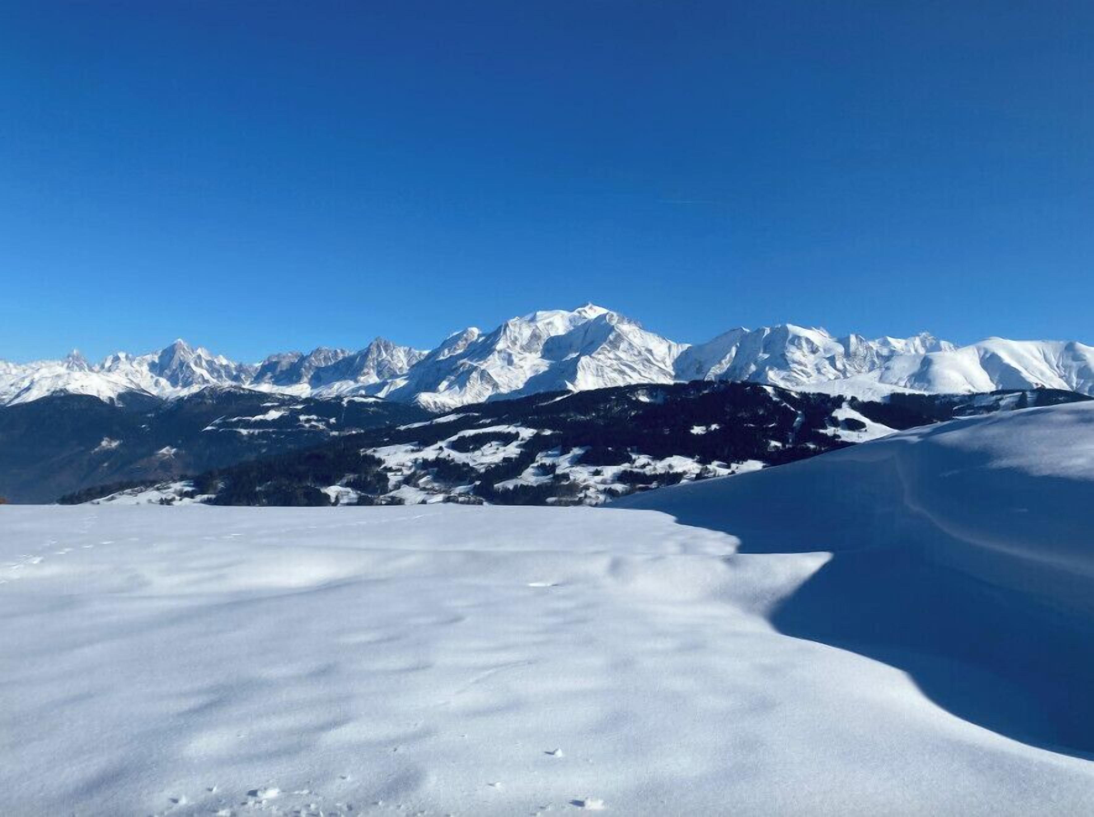 Un paysage montagneux enneigé, sous un ciel bleu dégagé.