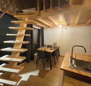 Un intérieur en bois comprenant un coin repas, une cuisine avec un évier et un escalier.