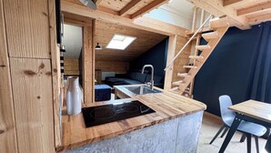 Een kleine keuken met een inbouwfornuis, een spoelbak en een eethoekje met een tafel en stoelen.