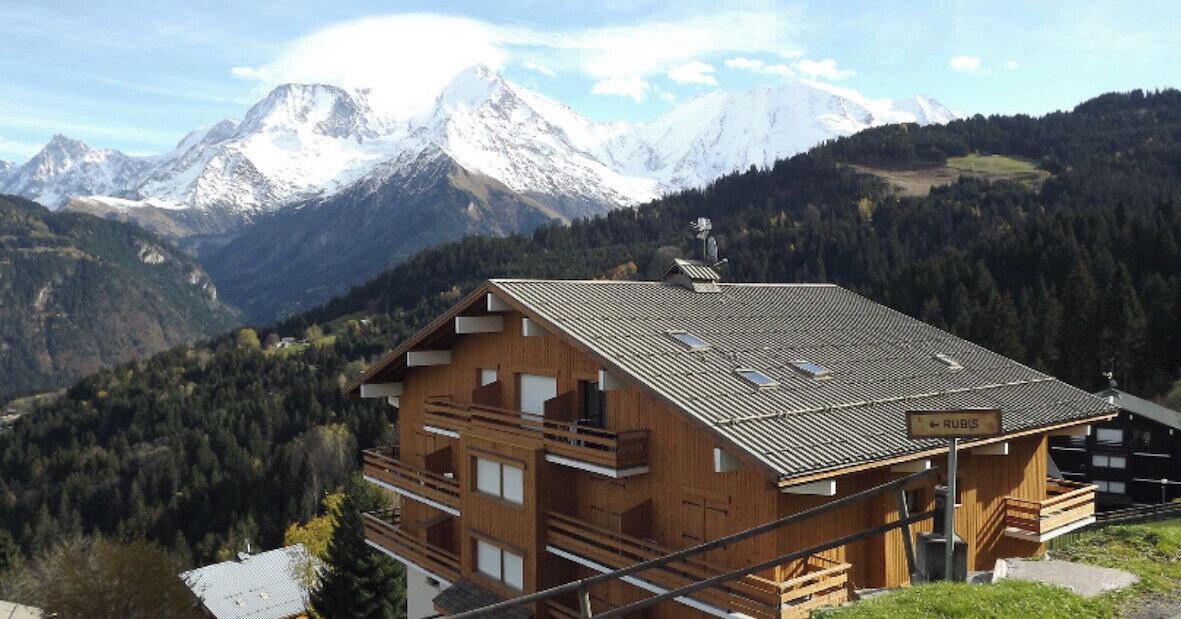 Eine Holzhütte mit geneigtem Dach und mehreren Balkonen, mit einem Schild mit der Aufschrift 'RUBIS'.