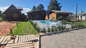 A residential area with a swimming pool, wooden deck, and houses with different architectural styles. - Cabins in Torres, RS, offering leisure and relaxation in a cozy and peaceful location. (Torres)
