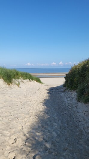 A sandy beach path leading to the ocean with clear skies. - Apartment 'Hanna' with Private Garden and Wi-Fi (Langeoog)