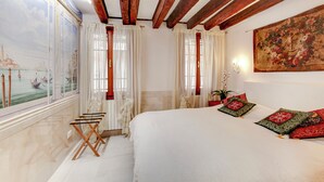 Een slaapkamer met een groot bed, houten balken, een muurschildering en een schilderij.