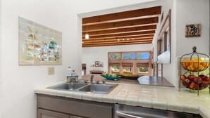 A modern kitchen with a double sink, stainless steel appliances, and a wooden ceiling. - Casa Golondrinas-A Serene Santa Fe Retreat (Santa Fe)