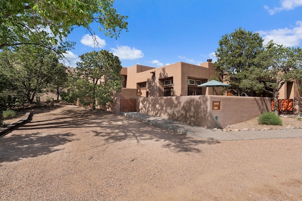 A desert-style building with a gravel driveway and surrounding trees.