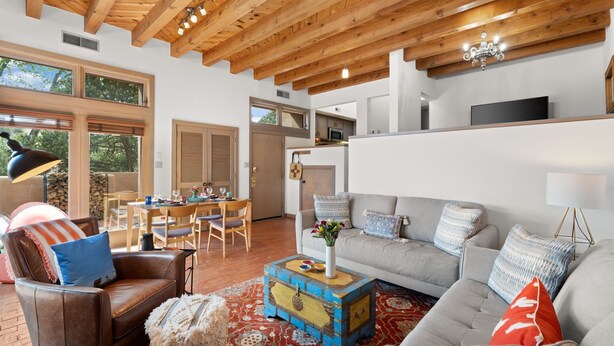 A spacious living area with a high wooden ceiling, a dining area, and a kitchen. - Casa Golondrinas-A Serene Santa Fe Retreat (Santa Fe)