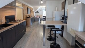 Et moderne køkken med en central ø, indbygget ovn og køleskab.