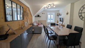 Et moderne køkken med træbordplade, et spisebord med stole, en sofa og et stort vindue.