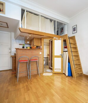 A compact kitchen with a wooden counter, two stools, and a small dining table. - Studio balcon proche Promenade des Anglais (Nice)