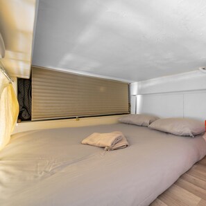 A single bed with a beige mattress, a folded beige towel, and two pillows. - Studio balcon proche Promenade des Anglais (Nice)