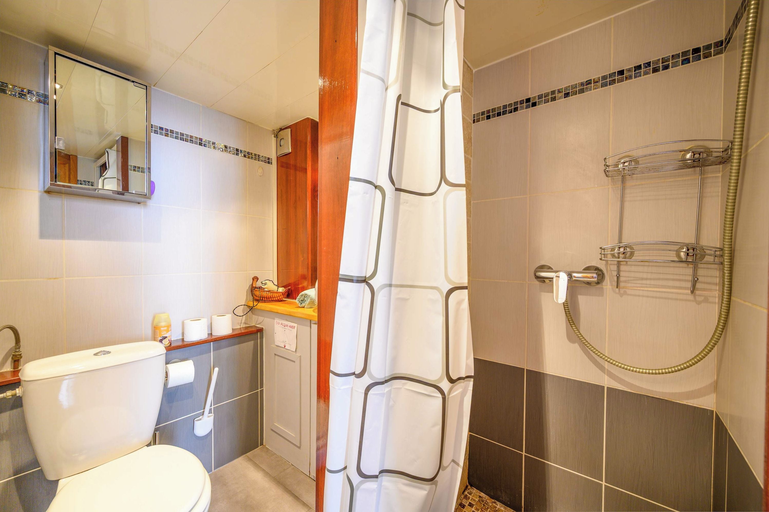 A bathroom with a toilet, sink, mirror, shower, and towel rack.