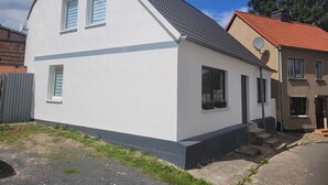 Una casa moderna de dos pisos con fachada blanca y techo gris.