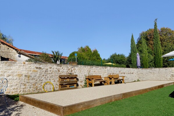 A courtyard with a stone wall, wooden benches, and a billiards table.