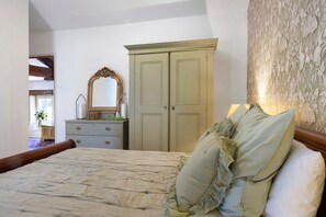 A bedroom with a large bed, a dresser, a mirror, and a wardrobe.