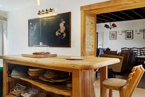 A wooden dining table with a glass cover, surrounded by wooden bowls and plates.