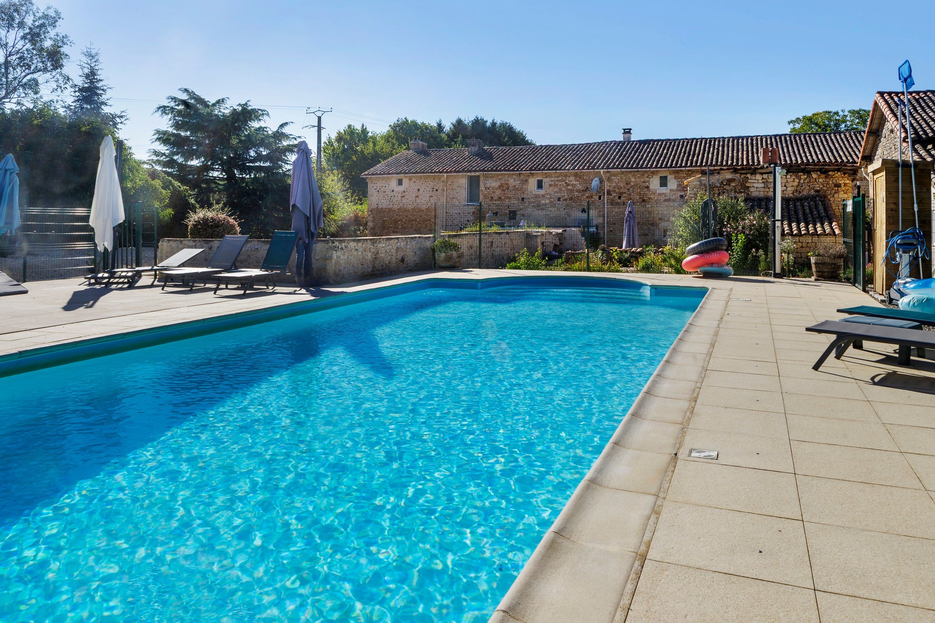 Ein rechteckiger Swimmingpool mit klarem, blauem Wasser, umgeben von einer gefliesten Liegefläche.