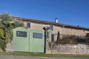A building with a green gate, a stone wall, and a metal fence.