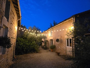 Ein Innenhof mit Steingebäuden, Lichterketten und Blumentöpfen.