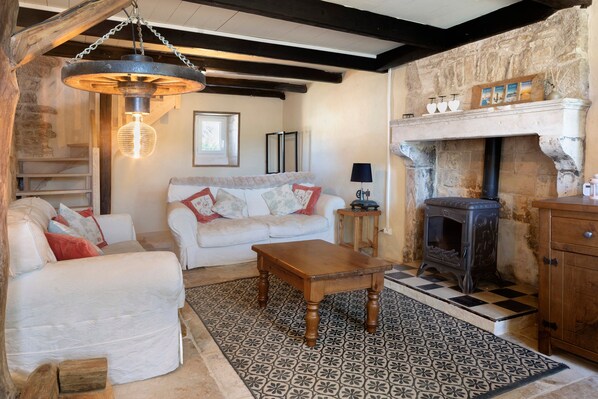 A cozy living room with a fireplace, a sofa, a coffee table, and a patterned rug.
