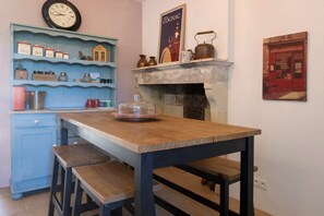 Eine Küche mit einem Holztisch, blauen Schränken und einer Uhr an der Wand.