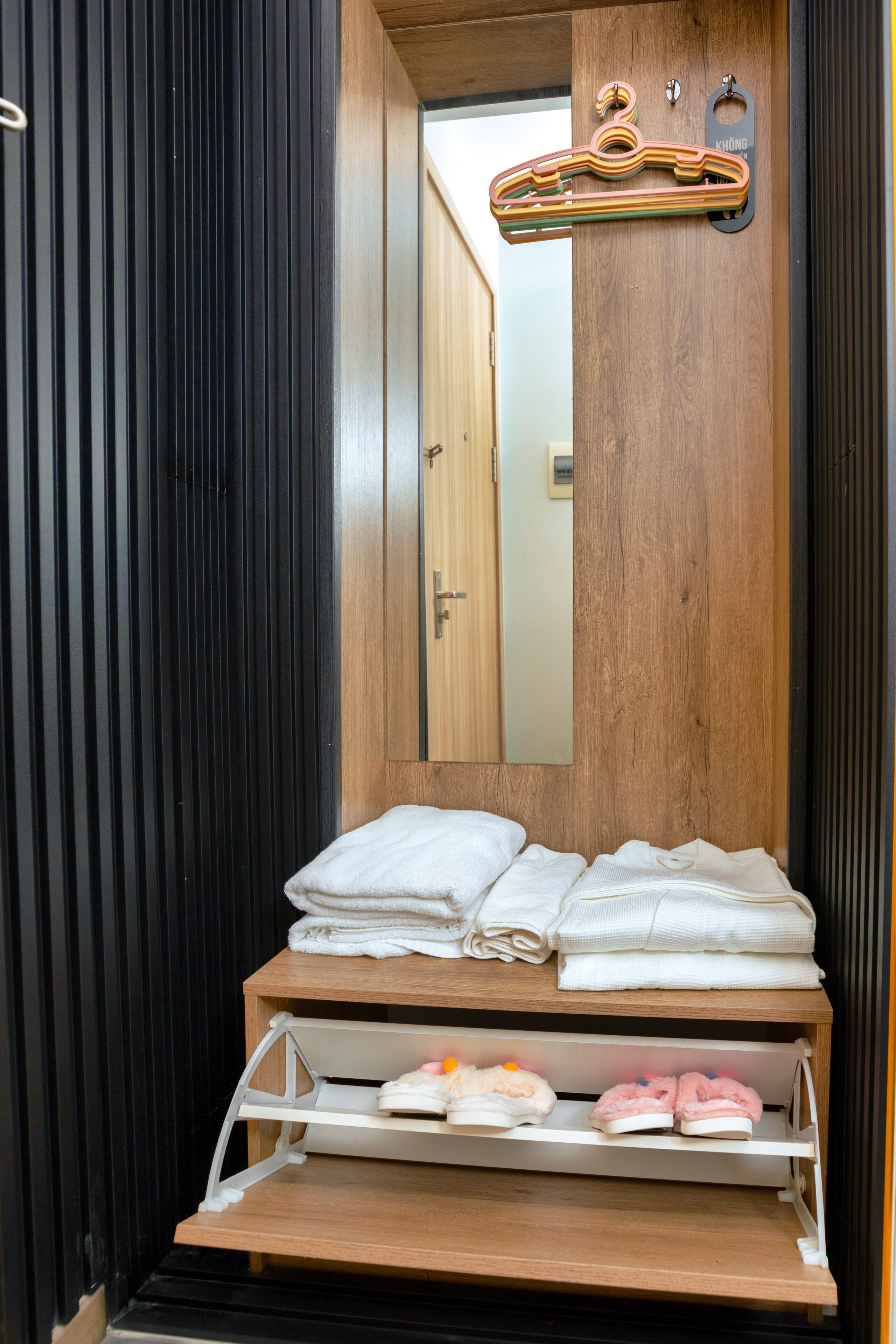 A bathroom with a wooden vanity, a mirror, and a towel rack with multiple towels.