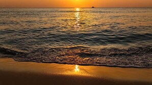 Un coucher de soleil sur une mer calme aux vagues douces.
