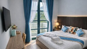 Une chambre d’hôtel moderne dotée d’un grand lit, d’un téléviseur à écran plat, d’une table de chevet en bois et offrant une vue sur l’extérieur.