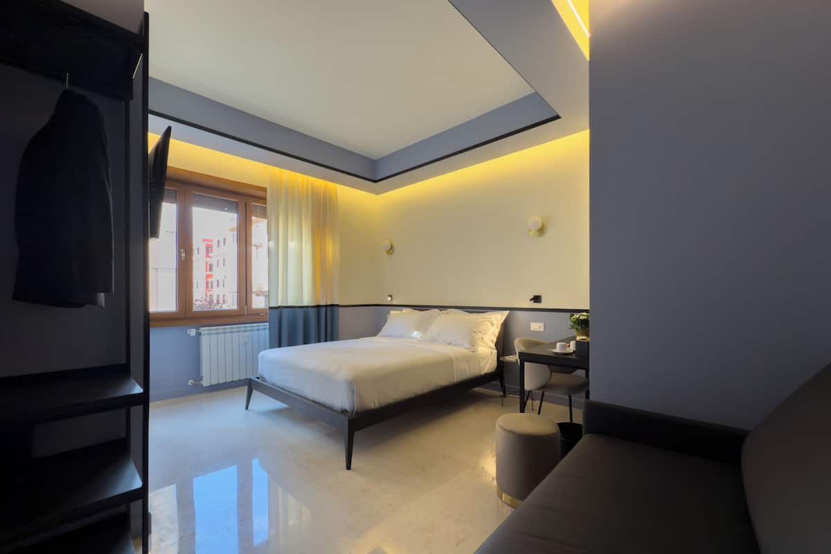 Una habitación de hotel moderna con una cama, un escritorio y un sofá.