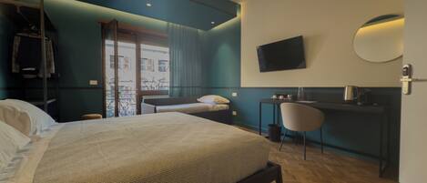 A modern hotel room with a large bed, a desk, a chair, and a TV on the wall.