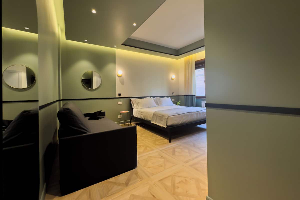 Una habitación de hotel moderna con cama, zona de estar y espejo.