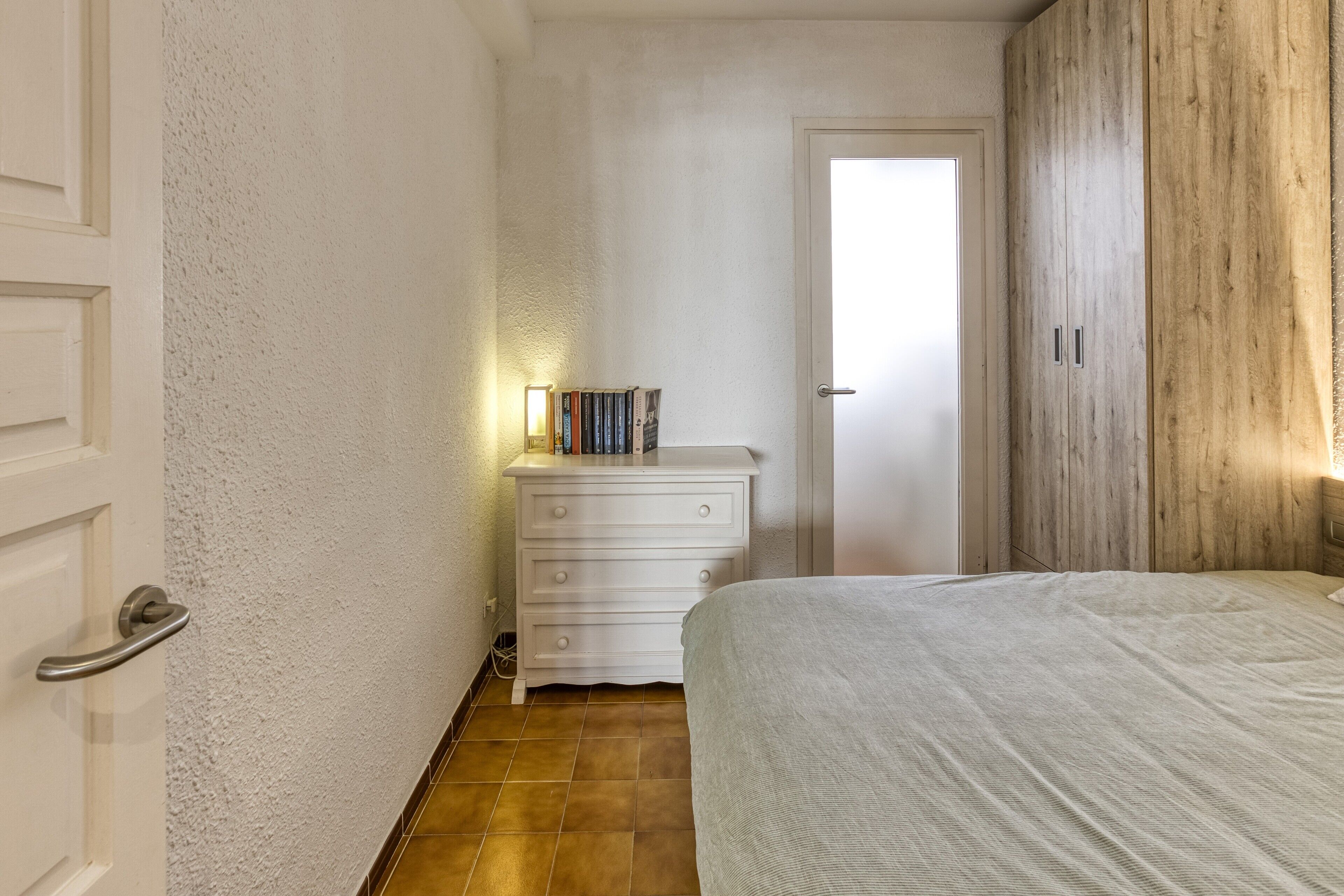 Ein Schlafzimmer mit Bett, Kommode und Tür.