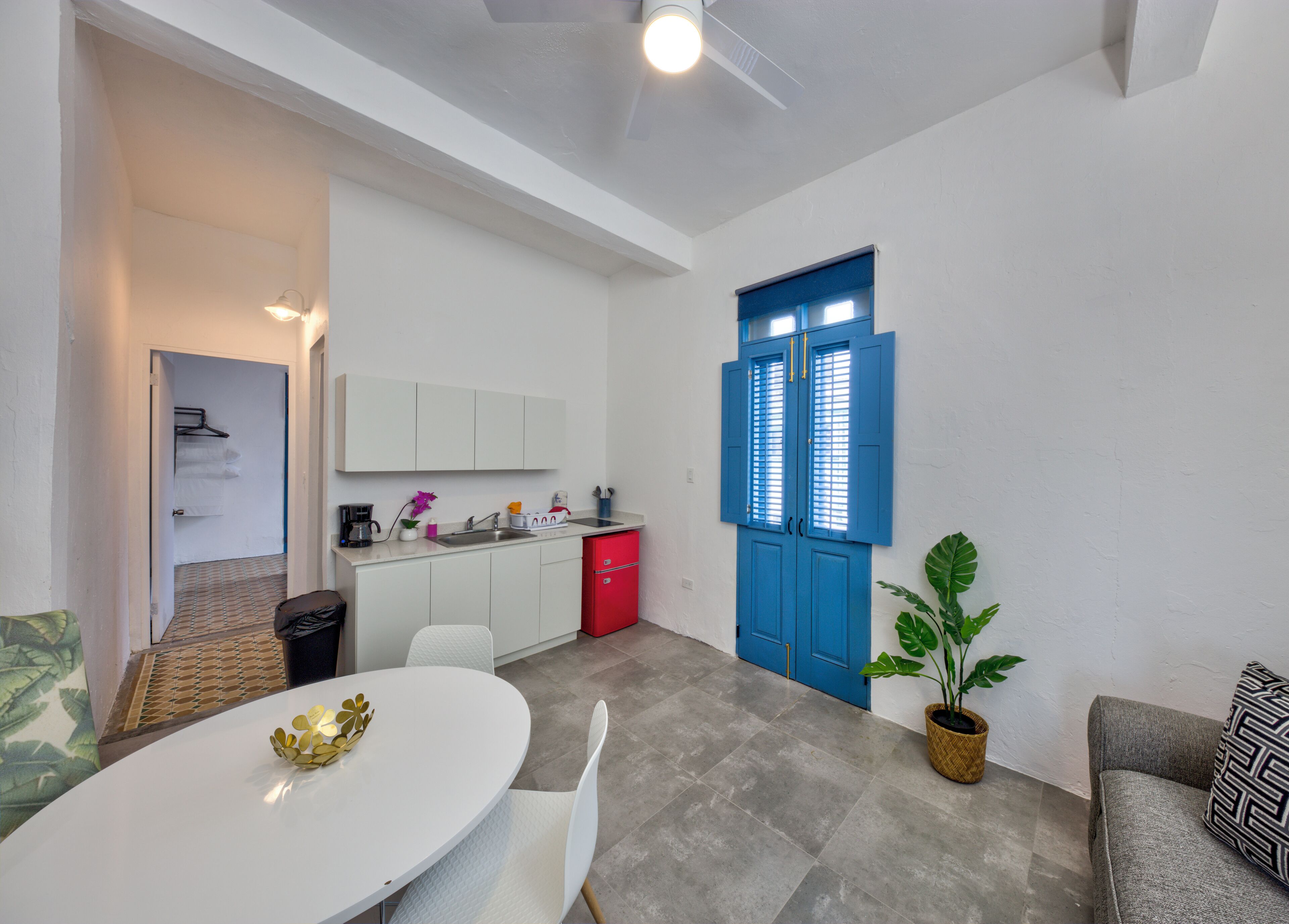 A compact living space with a dining area, kitchenette, and a blue door.