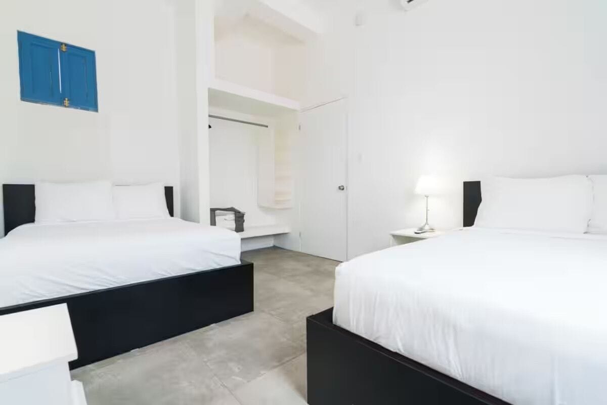Una habitación de hotel moderna con dos camas, un baño y una escalera.
