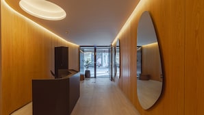 A modern reception area with wooden paneling, a reception desk, and a large mirror. - MOT Design SohoHaus (Buenos Aires)