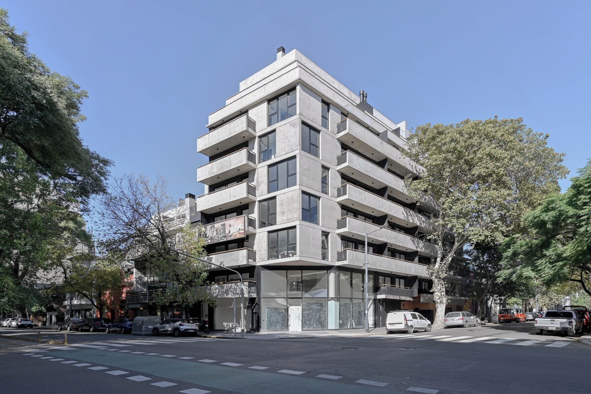 A multi-story building with a modern architectural design, featuring balconies and large windows.