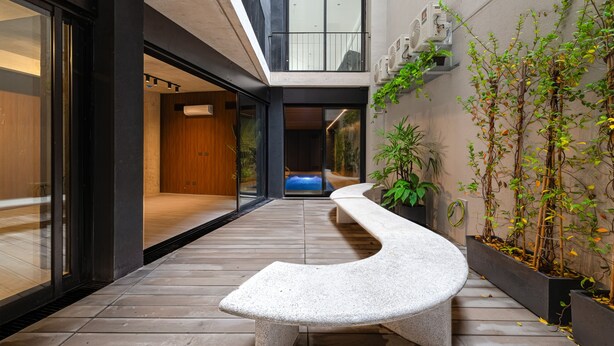 A modern interior with a curved bench, wooden flooring, and a view of a pool. - MOT Design SohoHaus (Buenos Aires)
