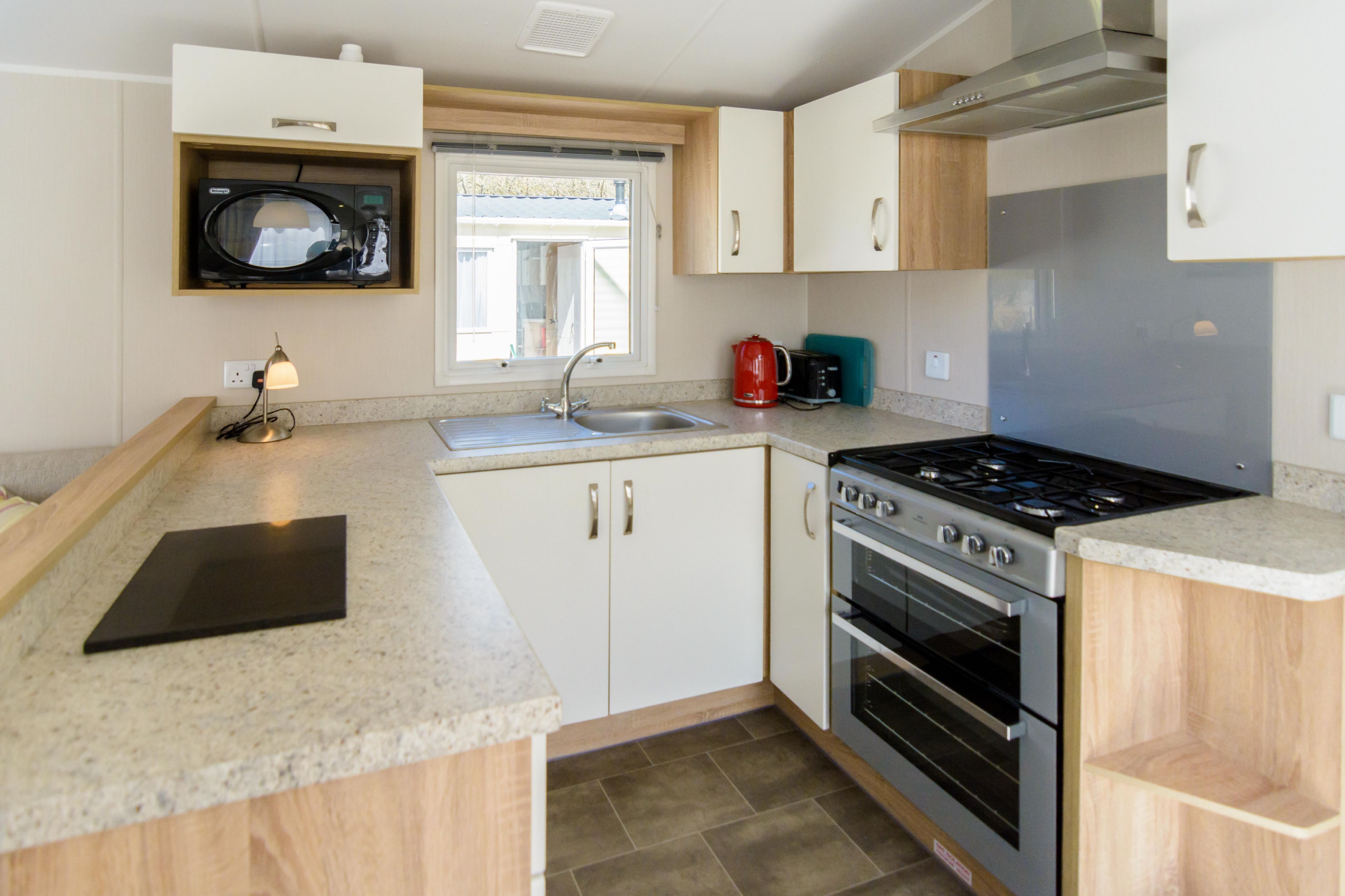 A compact kitchen with a built-in microwave, a gas stove, and a coffee maker.
