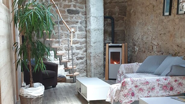 A rustic room with a stone wall, a wooden staircase, a fireplace, a bed, and a large potted plant. - A haven of peace in Rochepaule, in the heart of Ardèche verte (Rochepaule)