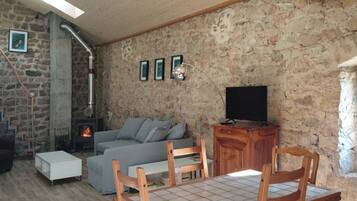 Un salon chaleureux avec un mur en pierre, une cheminée, un canapé, un téléviseur et des meubles en bois.